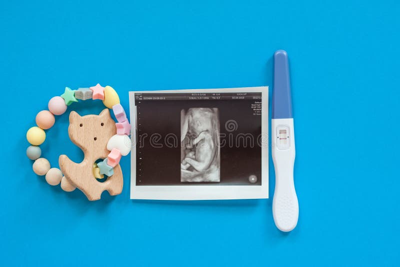 木质婴儿床,配有珠子、超声波图像和妊娠测试。 免版税库存图片 木质婴儿床,配有珠子、超声波图像和妊娠测试。 免版税库存图片