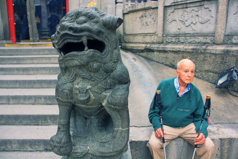 极老的欧洲男子北欧健走棍和神话中国皇狮护卫 免版税图库摄影 极老的欧洲男子北欧健走棍和神话中国皇狮护卫 免版税图库摄影