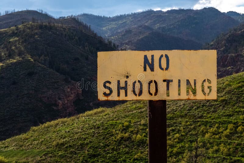 No shooting sign banning the use of guns and firearms with an outdoor nature background in the mountains. - gun ban. No shooting sign banning the use of guns and firearms with an outdoor nature background in the mountains. - gun ban.