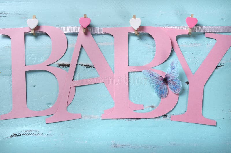 Pink baby girl nursery BABY letters bunting hanging from pegs on a line against a vintage aqua blue shabby chic background for baby shower or newborn girl greeting card. Pink baby girl nursery BABY letters bunting hanging from pegs on a line against a vintage aqua blue shabby chic background for baby shower or newborn girl greeting card.