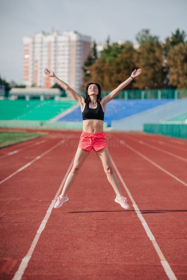 桃红色短裤和顶面做的锻炼的可爱的运动的深色的妇女与在太阳光芒的跳绳在体育场 免版税库存图片 桃红色短裤和顶面做的锻炼的可爱的运动的深色的妇女与在太阳光芒的跳绳在体育场 免版税库存图片