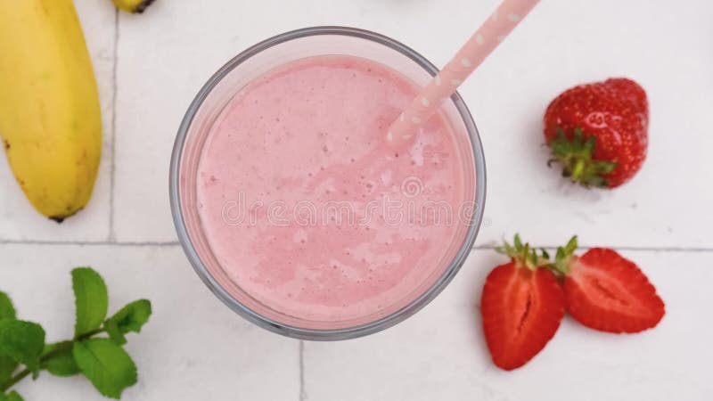 桌上放着稻草的草莓和香蕉奶昔的顶景. 健康饮品概念