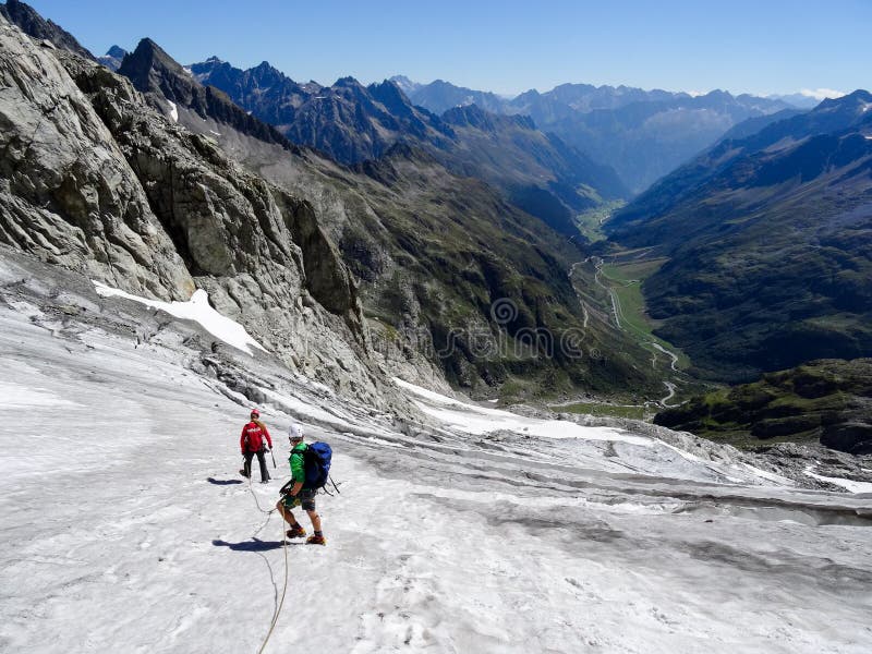 横渡在他们的途中的小组男性爬山者冰川下来从一个高高山峰顶