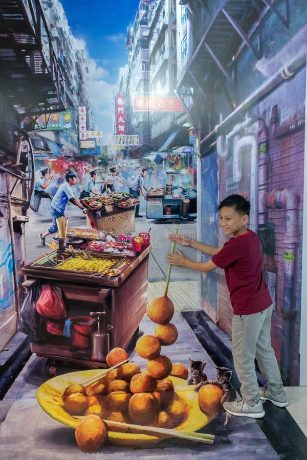 A young boy takes part in the trick-art photo, it is a realistic looking painting made to look real and 3d using shadows. the boy appears to be holding a skewer full of fish balls. A young boy takes part in the trick-art photo, it is a realistic looking painting made to look real and 3d using shadows. the boy appears to be holding a skewer full of fish balls