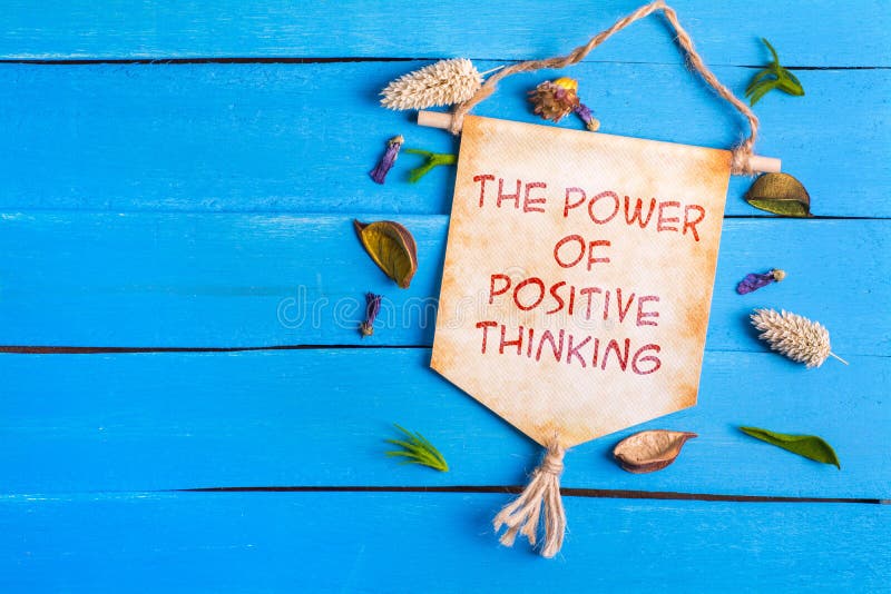 The power of positive thinking text on Paper Scroll with dried flower around and blue wooden background. The power of positive thinking text on Paper Scroll with dried flower around and blue wooden background