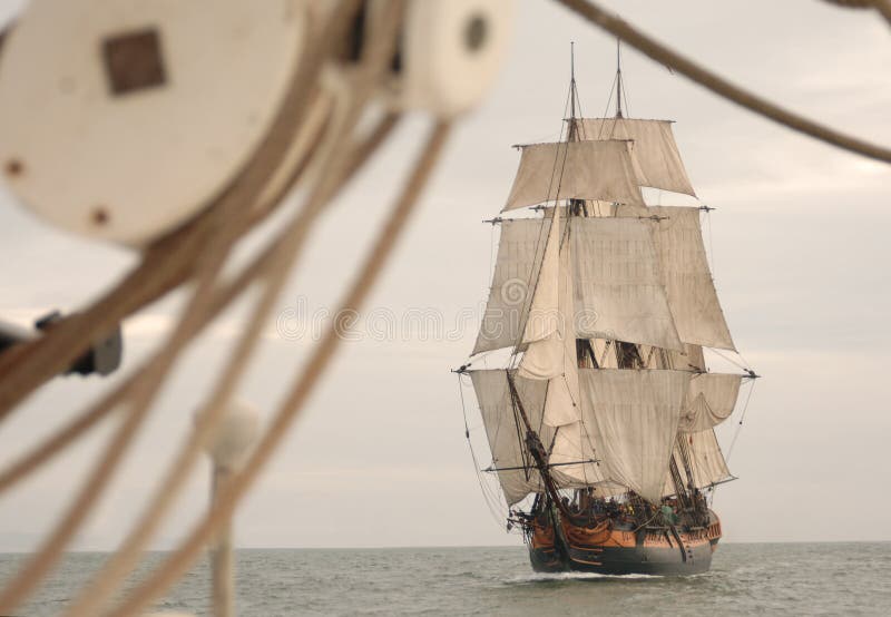 Vintage frigate viewed throught the rigging of another ship. Vintage frigate viewed throught the rigging of another ship