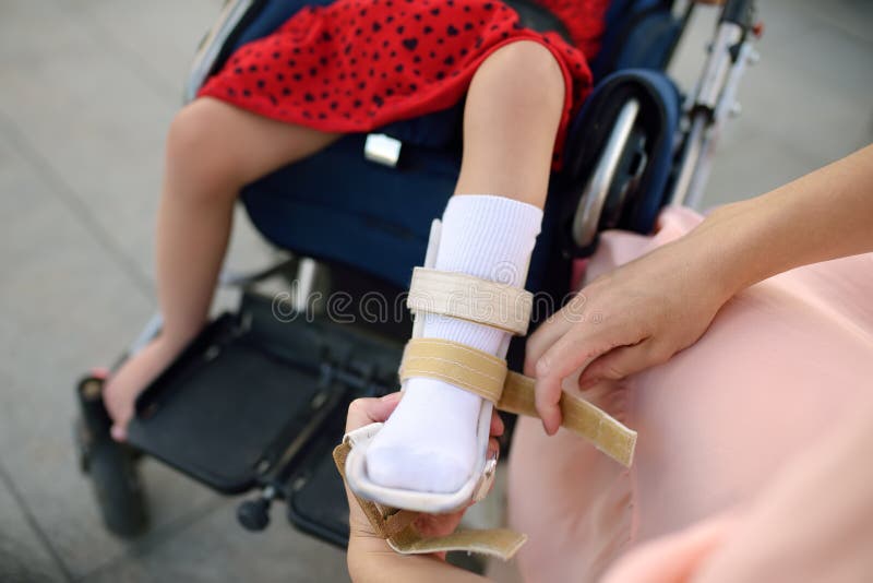 母亲投入整直法她的女儿腿 残疾女孩坐轮椅 儿童大脑麻痹 库存图片 母亲投入整直法她的女儿腿 残疾女孩坐轮椅 儿童大脑麻痹 库存图片