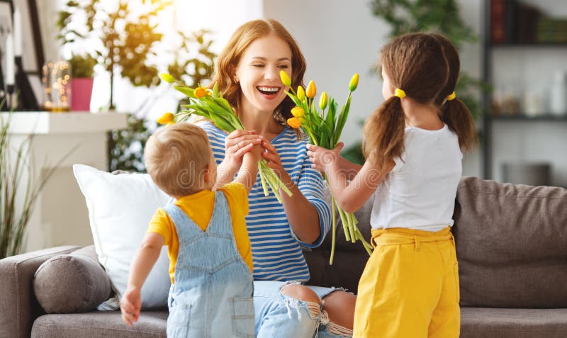 Happy mother`s day! Children congratulates moms and gives her a gift and flowers tulips. Happy mother`s day! Children congratulates moms and gives her a gift and flowers tulips