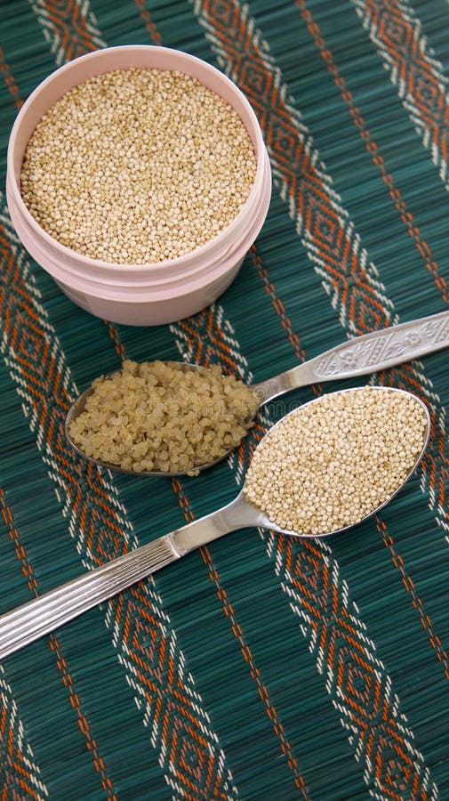 2 tablespoons of quinoa and round container with raw quinoa on the table. 2 tablespoons of quinoa and round container with raw quinoa on the table