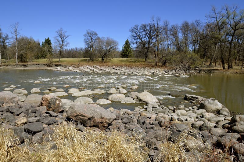 River water flows through rocks, this creating rapids in the springtime. River water flows through rocks, this creating rapids in the springtime.