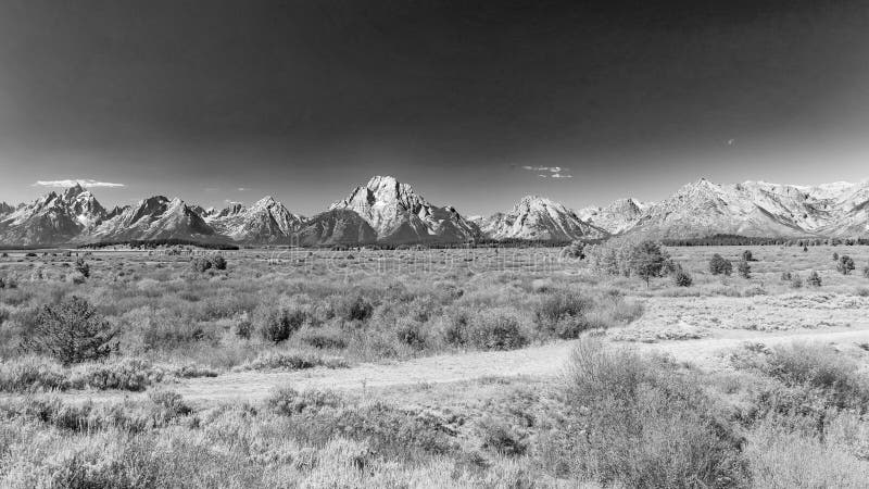 Wide shot of the whole range with Grand Teton on the left, Mount Moran in the middle and Eagle Rest Peak on the right. Broad plain of the potholes with only small shrubs growing because of the high water table. Most grasses and shrubs showing fall colors in early September. The higher peaks show some snow remnants from last winter. Deep haze from smoke from Canadian Forest Fires colors the horizon. Wide shot of the whole range with Grand Teton on the left, Mount Moran in the middle and Eagle Rest Peak on the right. Broad plain of the potholes with only small shrubs growing because of the high water table. Most grasses and shrubs showing fall colors in early September. The higher peaks show some snow remnants from last winter. Deep haze from smoke from Canadian Forest Fires colors the horizon.