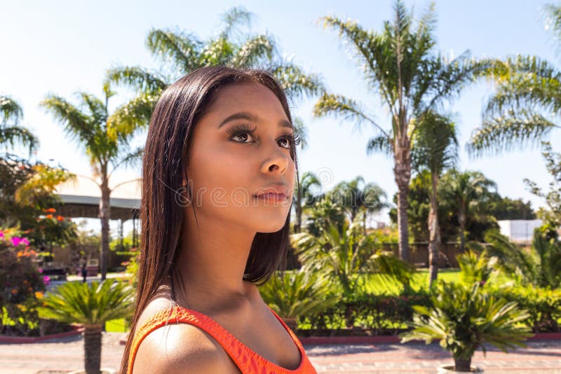 泳池边穿橙色泳衣的西班牙裔女性 免版税库存图片