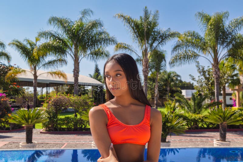 泳池边穿橙色泳衣的西班牙裔女性 库存图片