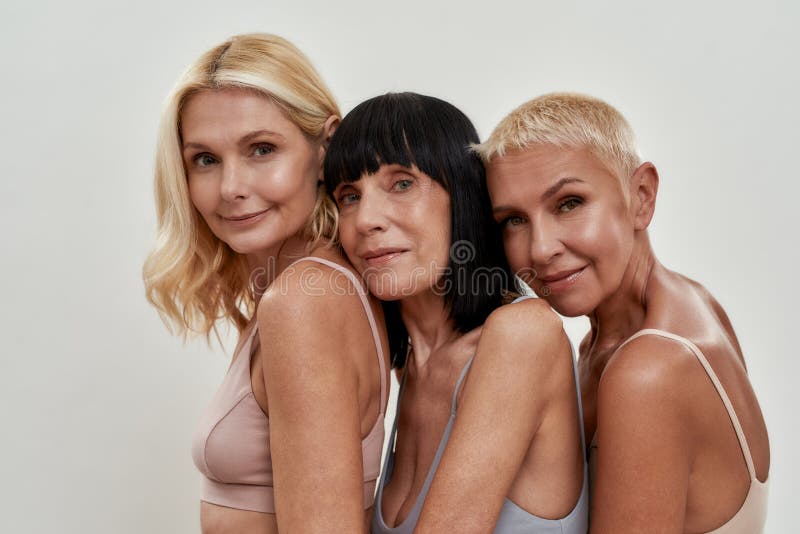 Close up portrait of three beautiful happy mature women in underwear posing together isolated over light background, smiling at camera. Beauty concept. Close up portrait of three beautiful happy mature women in underwear posing together isolated over light background, smiling at camera. Beauty concept