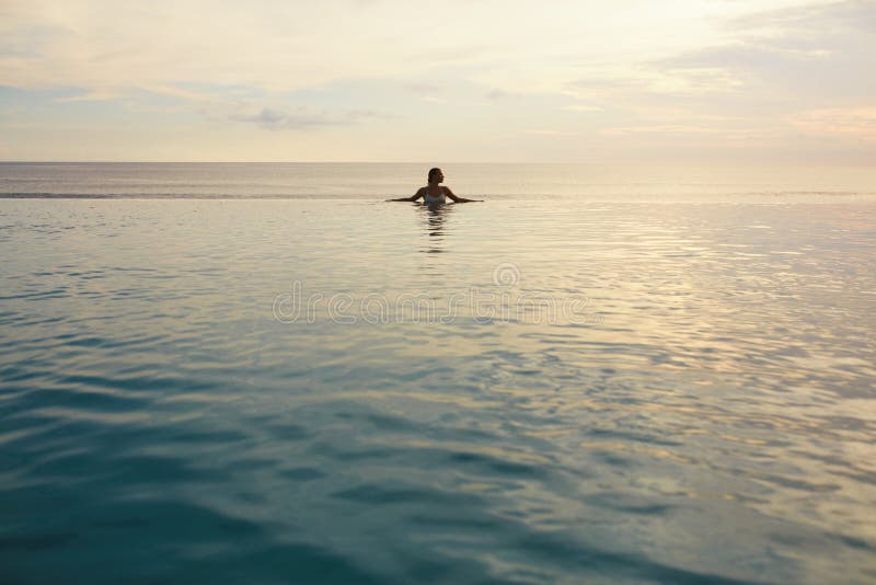Ocean. Woman Standing In Sea. Girl Touching Water Surface And Looking Away. Beautiful Seascape And Female Silhouette. Vacation In Tropical Country. Ocean. Woman Standing In Sea. Girl Touching Water Surface And Looking Away. Beautiful Seascape And Female Silhouette. Vacation In Tropical Country