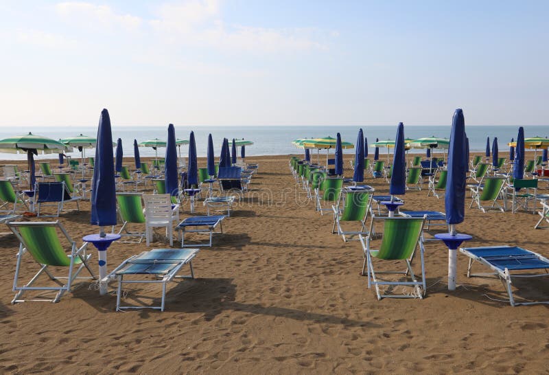 many closed blue sun umbrellas on the beach at the end of summer season. many closed blue sun umbrellas on the beach at the end of summer season