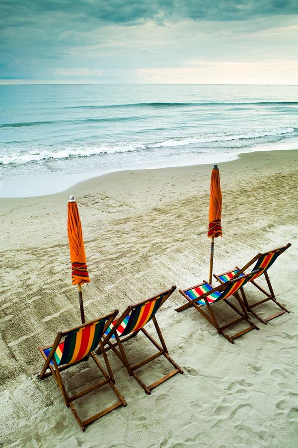 Empty beach with closed umbrellas and colorful deckchairs. Empty beach with closed umbrellas and colorful deckchairs.
