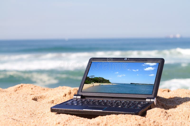 A black laptop on beach with beach picture on laptop screen. A black laptop on beach with beach picture on laptop screen