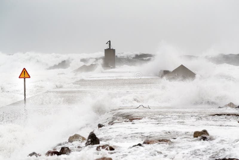 Storm in the sea with enormous waves invading the levee. A sign of danger notices of the risk. Storm in the sea with enormous waves invading the levee. A sign of danger notices of the risk