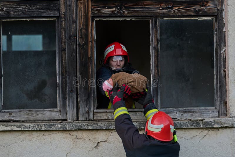 消防员从窗户救出一个婴儿，紧急情况，团队合作和勇敢，消防员行动，拯救 免版税库存图片