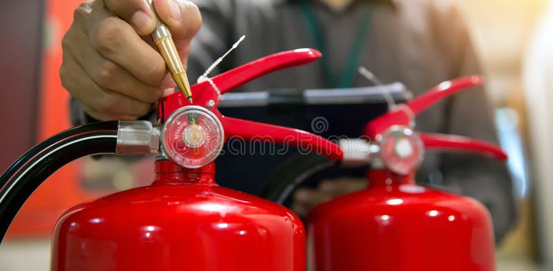 Firefighter are checking fire extinguishers tank in the building concepts of prevention safety training for emergency rescue and fire drill. Firefighter are checking fire extinguishers tank in the building concepts of prevention safety training for emergency rescue and fire drill