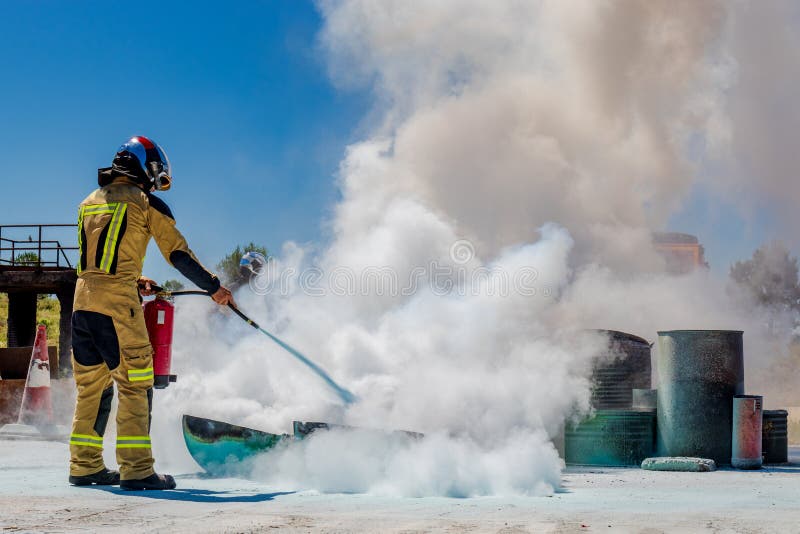 Firefighter putting out a fire with a fire extinguisher helmet and protections. Firefighter putting out a fire with a fire extinguisher helmet and protections