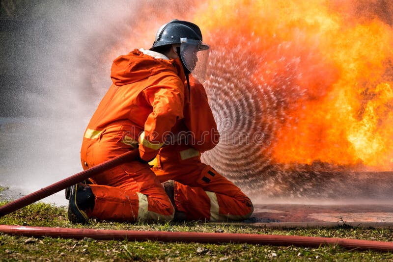 Firefighter is spraying water to extinguish the fire in training center. Firefighter is spraying water to extinguish the fire in training center.