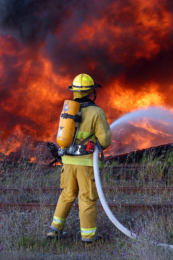 Firefighter advances hose line on burn pile. Firefighter advances hose line on burn pile