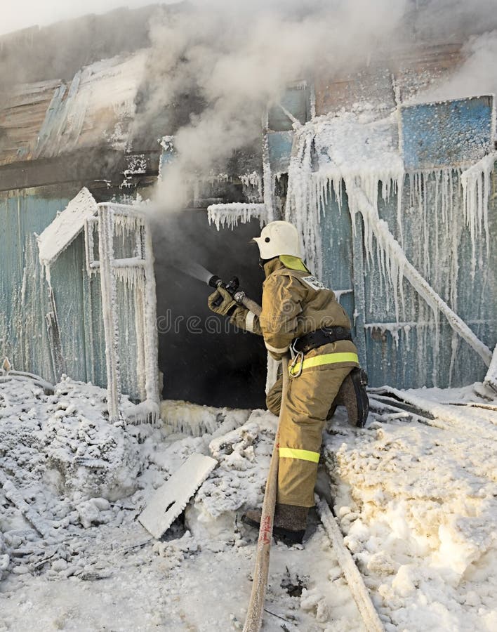 Firefighter extinguishes a fire in a wooden house. Firefighter extinguishes a fire in a wooden house