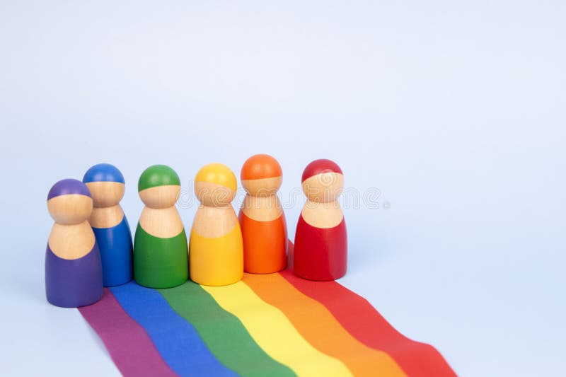 淡蓝色背景中的木人塑像和LGBTQ彩虹旗. 多样性和包容性概念 免版税库存图片