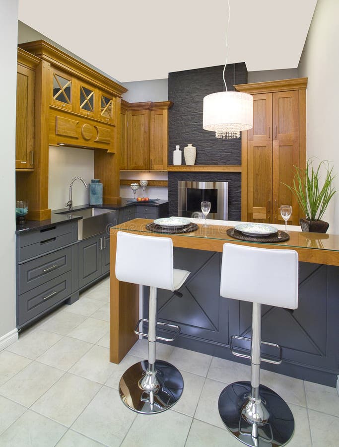 Dark grey and brown wooden kitchen with an island and 2 white stools. Dark grey and brown wooden kitchen with an island and 2 white stools