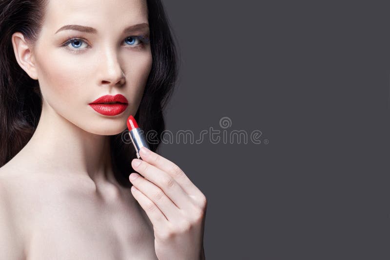 年轻深色的妇女绘她的嘴唇明亮的红色唇膏 明亮的晚上构成 赤裸女孩照料她的面孔和嘴唇 免版税图库摄影 年轻深色的妇女绘她的嘴唇明亮的红色唇膏 明亮的晚上构成 赤裸女孩照料她的面孔和嘴唇 免版税图库摄影