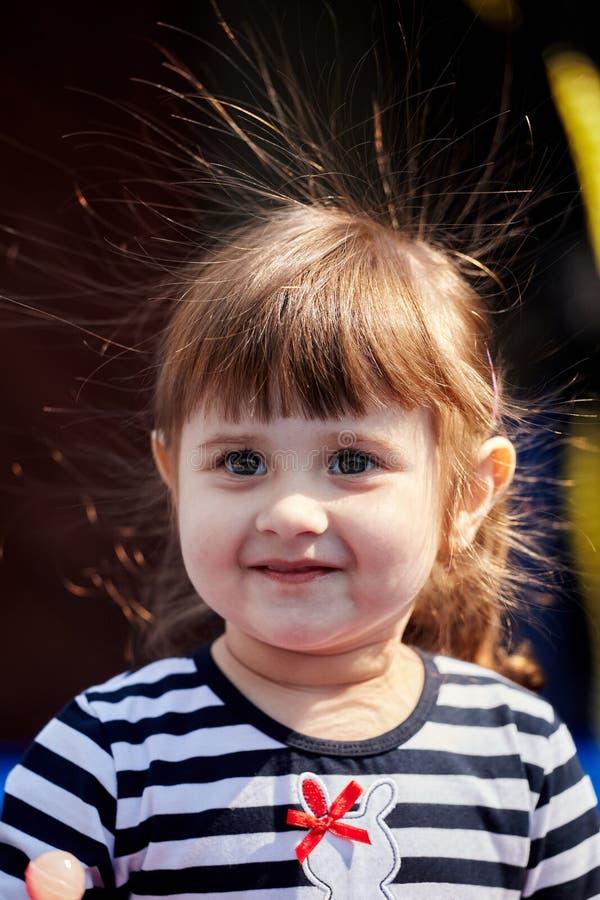 Portrait of a girl with electrified hair on a dark background. Cute small kid girl. Closeup portrait. Electricity power concept. Portrait of a girl with electrified hair on a dark background. Cute small kid girl. Closeup portrait. Electricity power concept