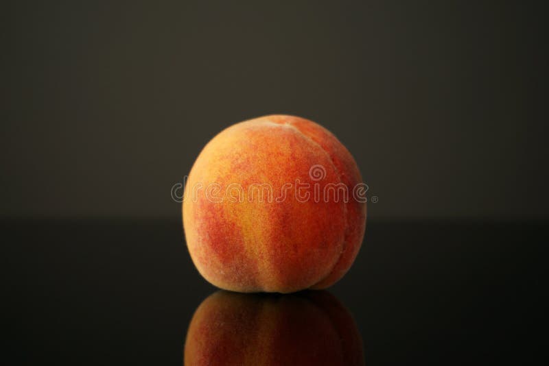 深色背景中的桃子躺在桌子上. 多汁的成熟美丽反映在桌子的黑玻璃上