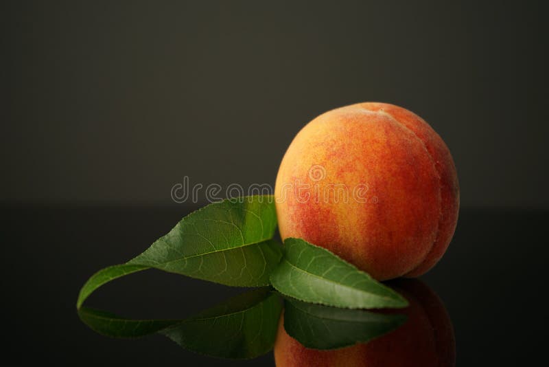 深色背景中的桃子躺在桌子上. 多汁的成熟美丽反映在桌子的黑玻璃上