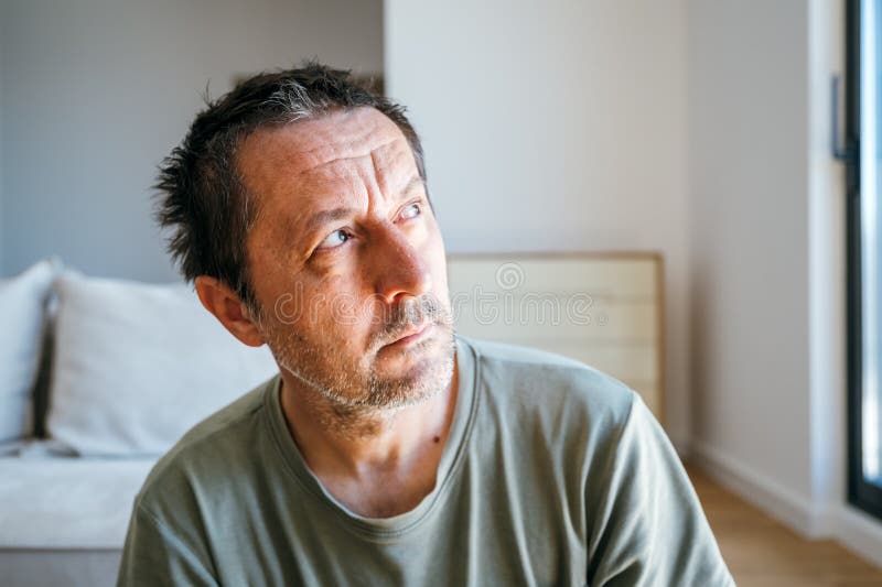 清晨坐在客厅里思考、望窗的沉思男人肖像 免版税库存照片