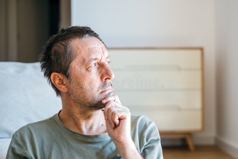 清晨坐在客厅里思考、望窗的沉思男人肖像 免版税库存照片
