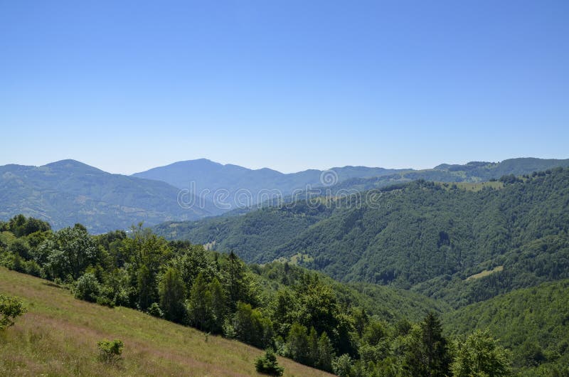 清澈蓝天下，青山起伏的宁静山景 库存照片