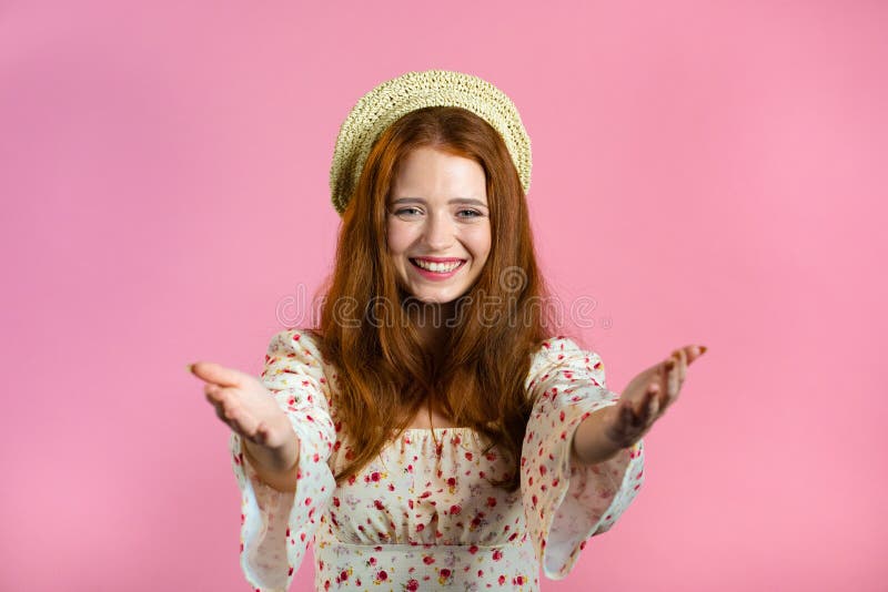 Beautiful woman showing - Hey you, come here. Girl in floral dress ask join her, beckons with inviting hand hugs gesture. Lady is looking playful flirtatious, inviting to come. Pink studio background. Beautiful woman showing - Hey you, come here. Girl in floral dress ask join her, beckons with inviting hand hugs gesture. Lady is looking playful flirtatious, inviting to come. Pink studio background