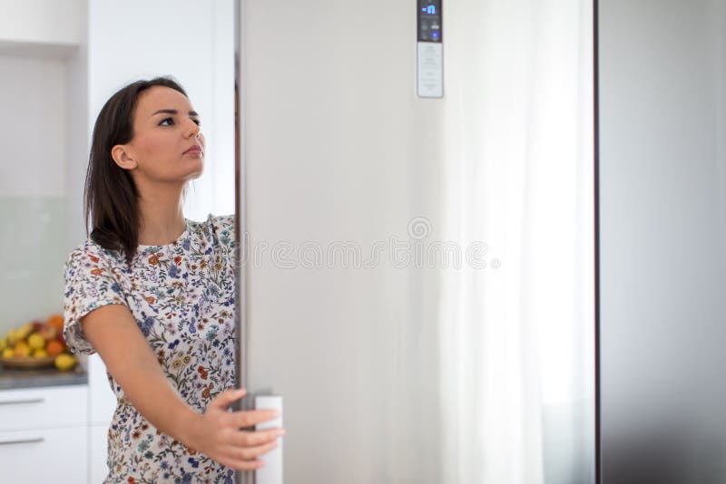 Pretty, young woman in her modern kitchen, by the fridge, about to cook a healthy meel for her family color toned image. Pretty, young woman in her modern kitchen, by the fridge, about to cook a healthy meel for her family color toned image