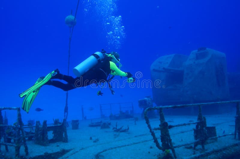 A diver hovers above the deck of a sunken Russian frigate in front of one of the double-barreled guns. A diver hovers above the deck of a sunken Russian frigate in front of one of the double-barreled guns.