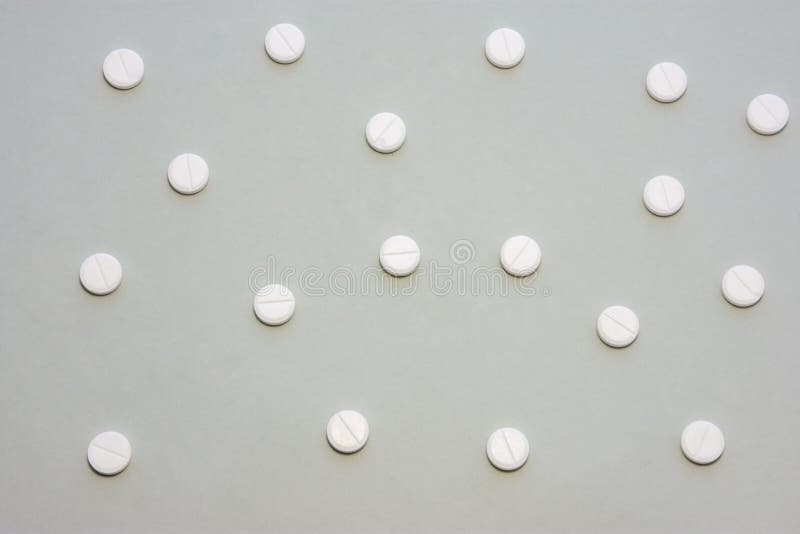 白色药片散落在灰色背景上形成斑驳的装饰图案。用于医药、药房、药品生产的照片 免版税图库摄影