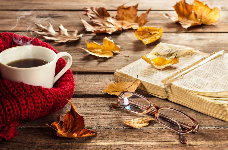 热的咖啡、书、玻璃和秋叶在木背景
