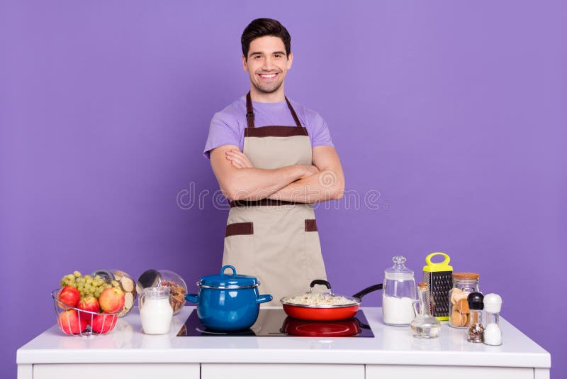 照片上，穿着灰色围裙的相当自信的男人穿着一件现成的美味菜肴，突显紫色背景