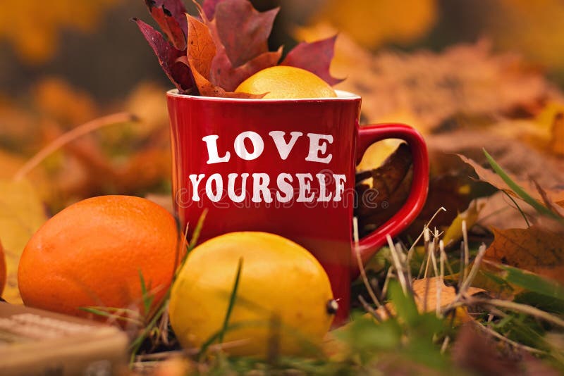 Words Love yourself written on red mug. Selective focus and noise. Shallow depth of field on the mug. Words Love yourself written on red mug. Selective focus and noise. Shallow depth of field on the mug