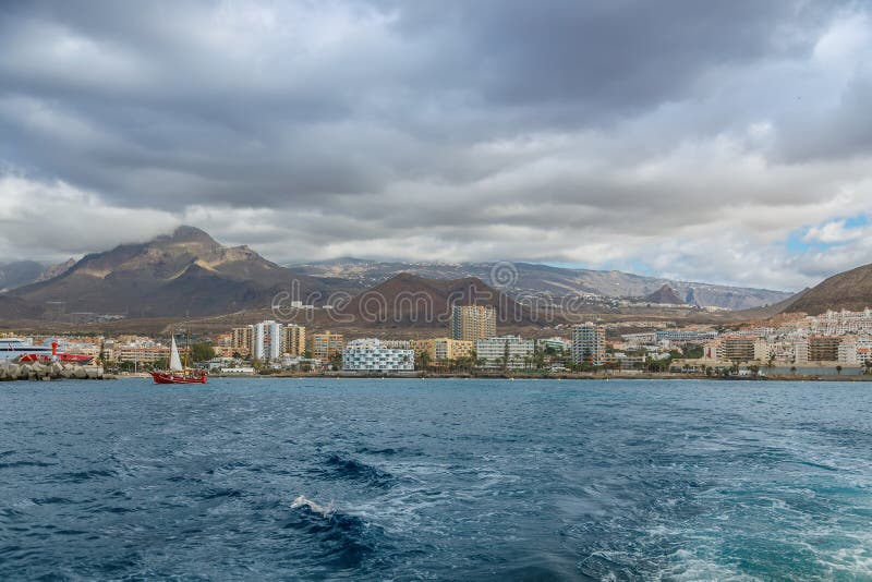 特内里费沿海城市景观，现代酒店和从海洋水域出发的山脉，为加那利群岛旅行提供概念 库存图片