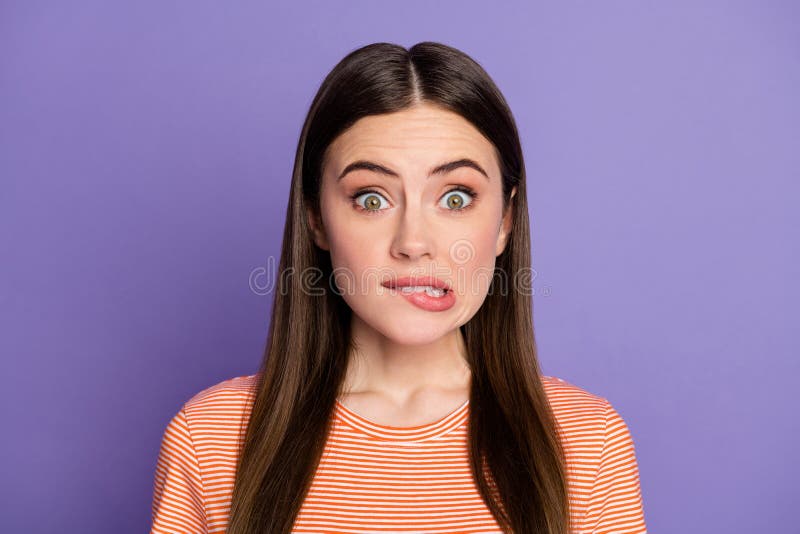 特写照片：漂亮受惊的女士咬嘴唇大错特错，满眼恐惧，穿橙色休闲装感觉愧疚 免版税库存照片