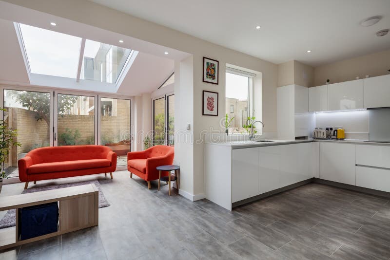 Trumpington, Cambridge, England - Feb 2 2019: Luxury modern contemporary fitted kitchen open plan to living area with bifold doors leading to courtyard garden. Trumpington, Cambridge, England - Feb 2 2019: Luxury modern contemporary fitted kitchen open plan to living area with bifold doors leading to courtyard garden