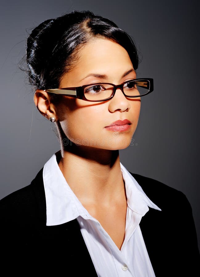 Mixed race woman looks away with spectacles and a suit, in dramatic lighting. Mixed race woman looks away with spectacles and a suit, in dramatic lighting