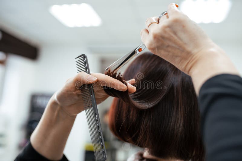 The work of a hairdresser. Hairdresser cut hair of a woman  in a beauty salon. Close-up of hands. The work of a hairdresser. Hairdresser cut hair of a woman  in a beauty salon. Close-up of hands
